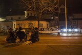 A group sits outside of the police station after five people weer shot.