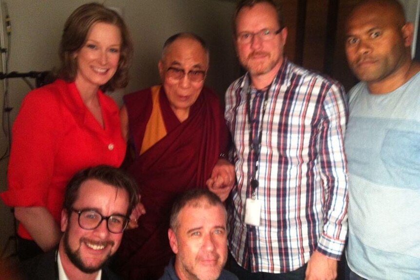 Woman and men in group around the Dalai Lama.