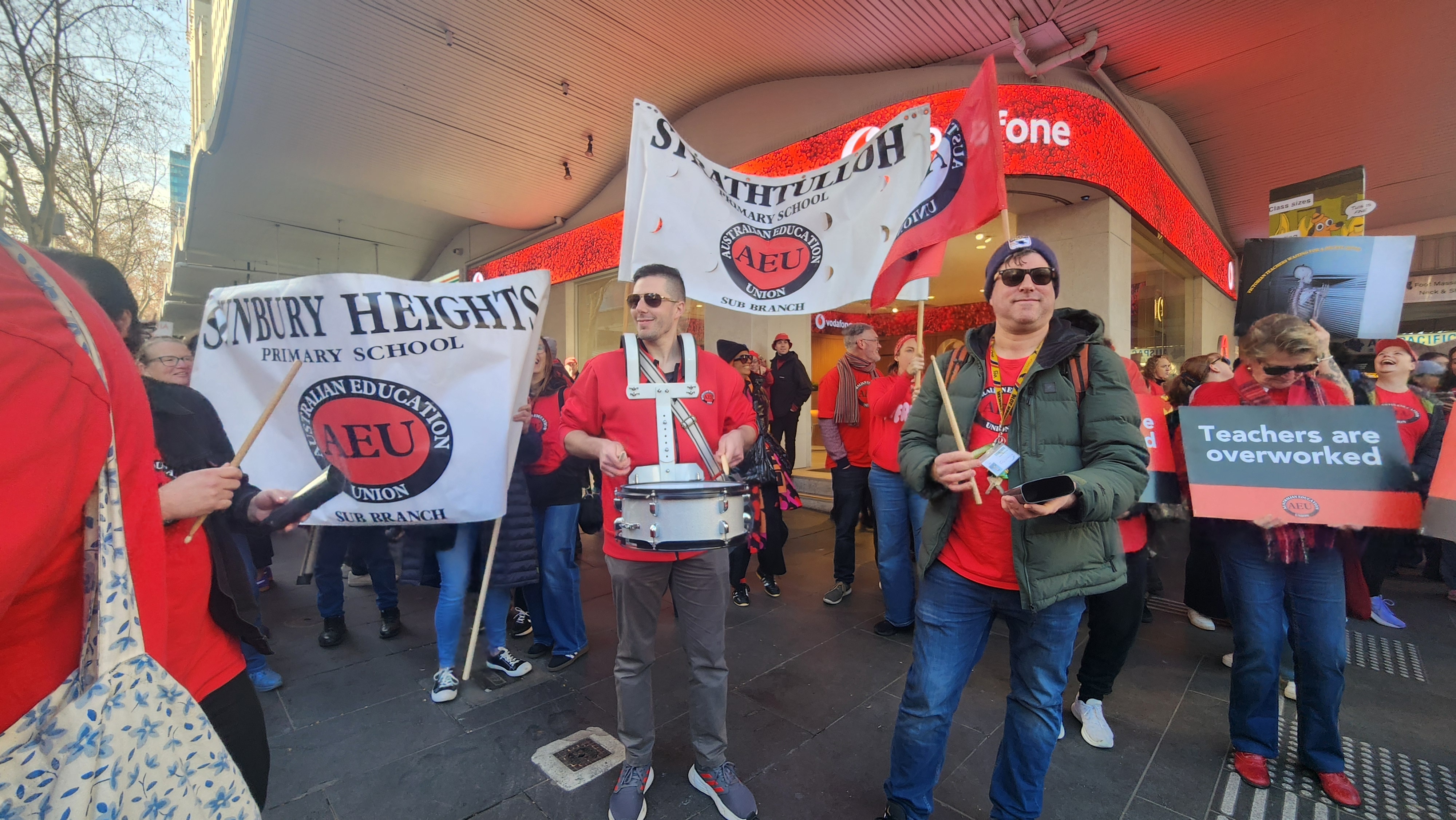 Men and women dressed in red carry placards and flags.
