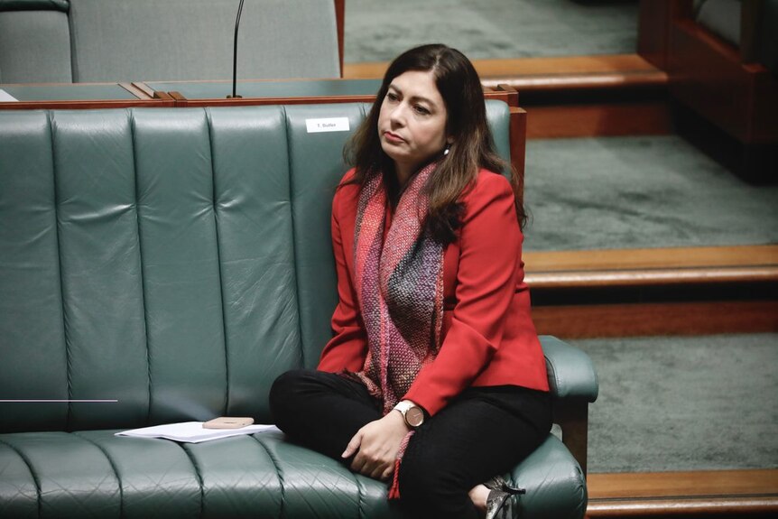 A woman in a red blazer sits on the bench in the House of Representatives