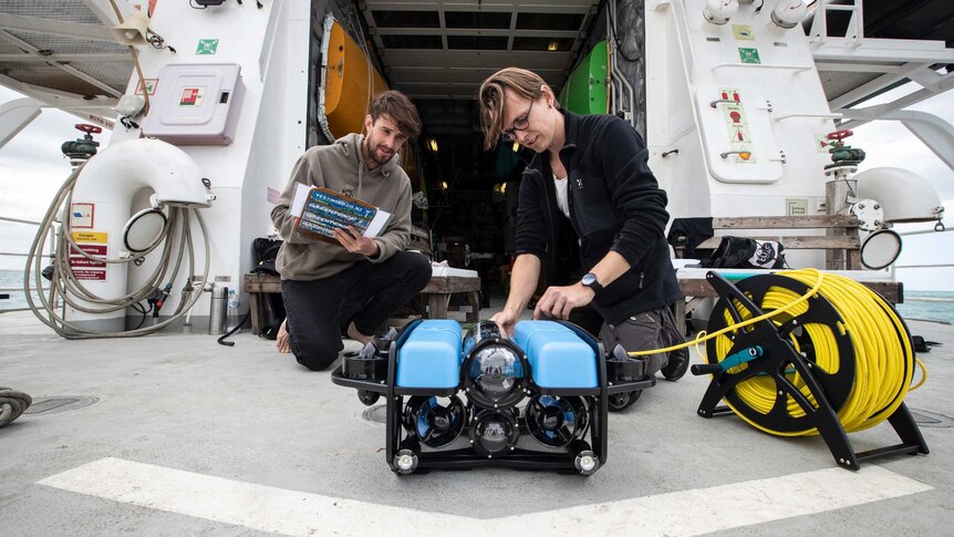 Two men on the deck of the Rainbow Warrior tend to an ROV.