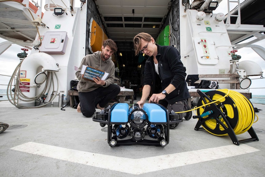 Two men on the deck of the Rainbow Warrior tend to an ROV.