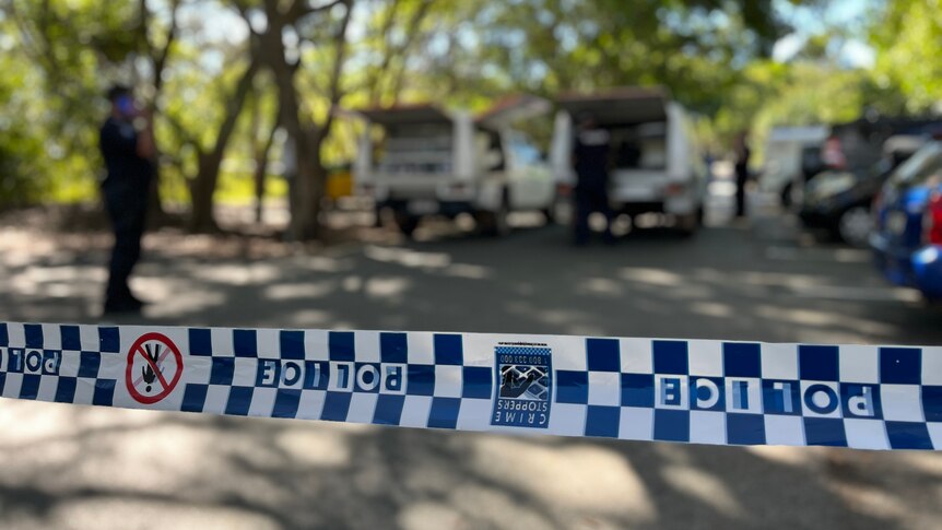Queensland Police officers stand near vehicles at crime scene