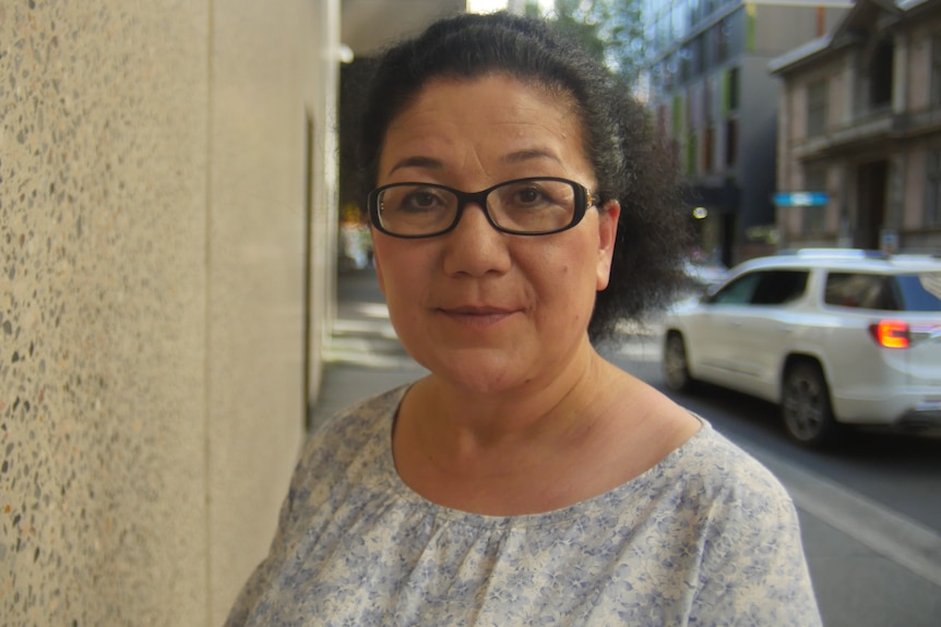 A woman wearing glasses looks over her shoulder.