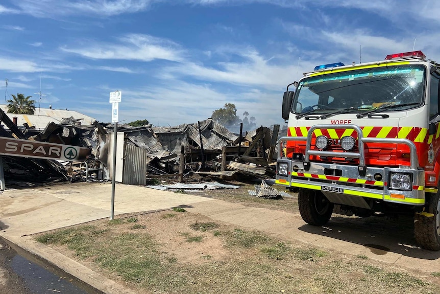 The burnt rubble of the SPAR shop with a fire truck to the side of the photo