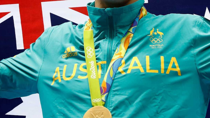 Cropped image of Kyle Chalmers standing on the Olympic podium with a gold medal.