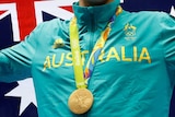 Cropped image of Kyle Chalmers standing on the Olympic podium with a gold medal.