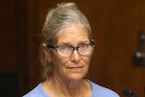 Leslie Van Houten in prison blues wearing glasses in a courtroom 