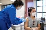 A woman with a mask on receives her first dose of the COVID-19 vaccine in Ohio.
