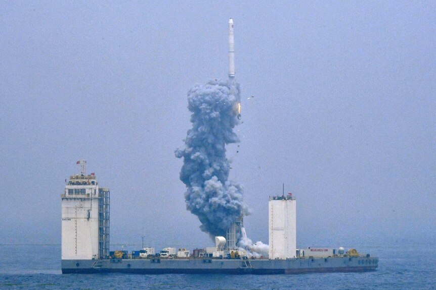 A grainy photo showing a rocket being launched into space from a sea platform