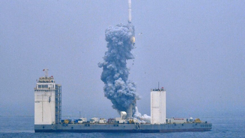 A grainy photo showing a rocket being launched into space from a sea platform