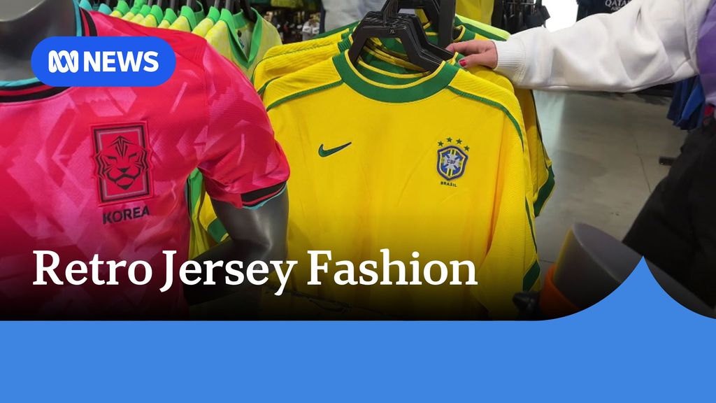 Retro Jersey Fashion: An unseen person's hand holds a yellow soccer jersey on a rack.