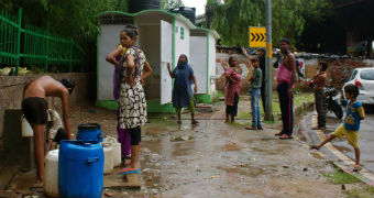 Residents of a slum built under an overpass in South Delhi collect water next to toilets installed for them.