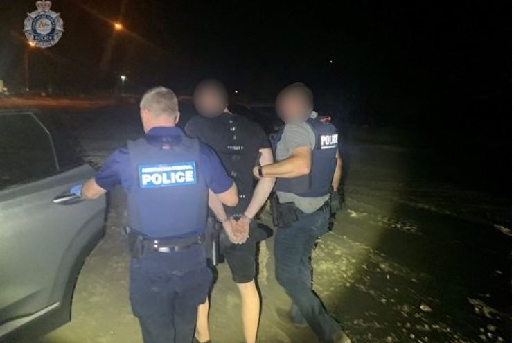 Police arresting a hand-cuffed man, faces blurred