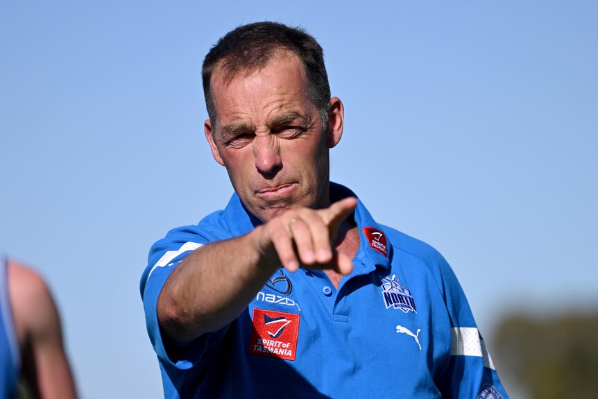 Coach Alastair Clarkson points while wearing North Melbourne Kangaroos training gear.