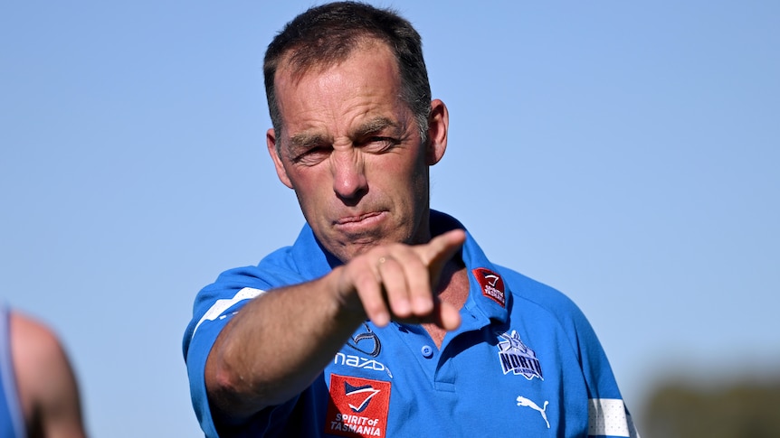 Coach Alastair Clarkson points while wearing North Melbourne Kangaroos training gear.
