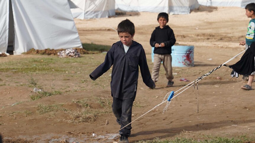 Humzeh Sharrouf walks through a Syrian refugee camp