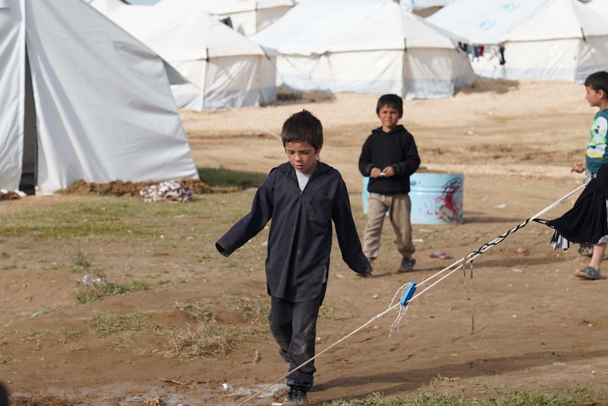 Humzeh Sharrouf walks through a Syrian refugee camp