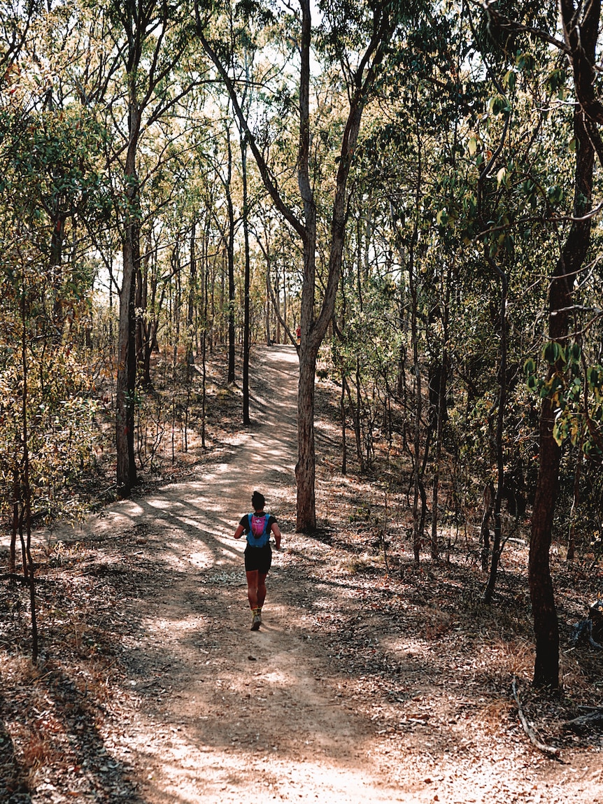 Ultra marathon runner Jacqui Bell runs in the bush along a dirt track.