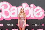Margot Robbie wearing a pale pink sequined strapless mini dress with coreset-like detailing and sheer heels