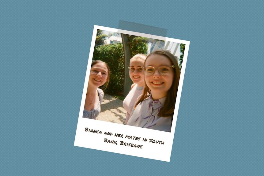 A young woman with glasses stands under an archway with two friends