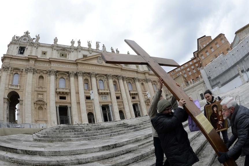 Faithful carry cross on steps of St Peter's