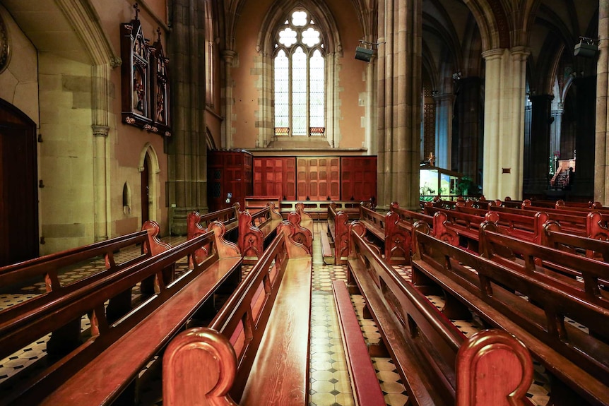 Light shines through an arch window onto two rows of pews inside St Patrick's Cathedral.