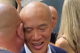 Bald man hugs another man in a crowd