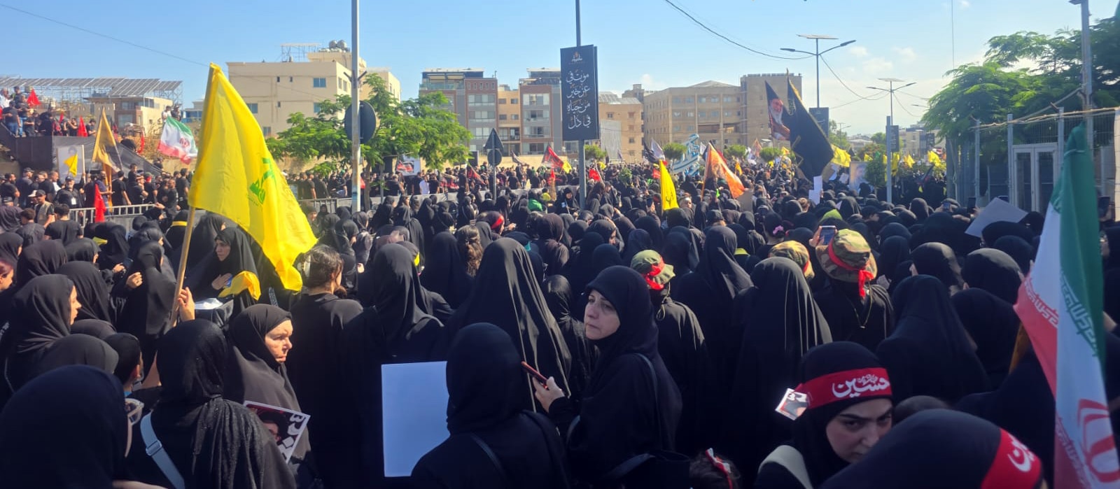 Dozens of women wearing black, and holding up Iranian and Lebanese flags.