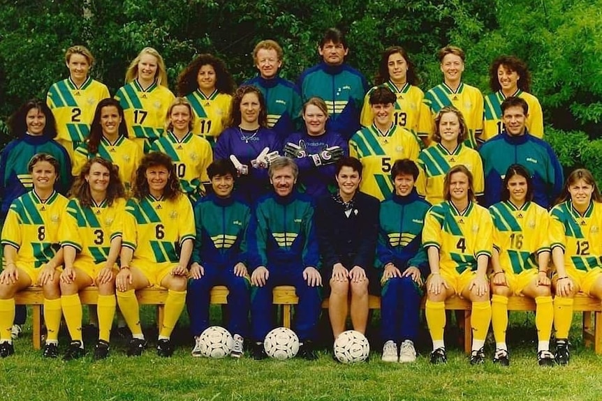 A women's soccer team wearing yellow and green poses for a photo