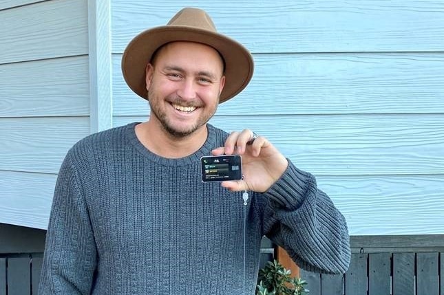 Man in a hat holding up a pumping unit to help control blood sugar levels.