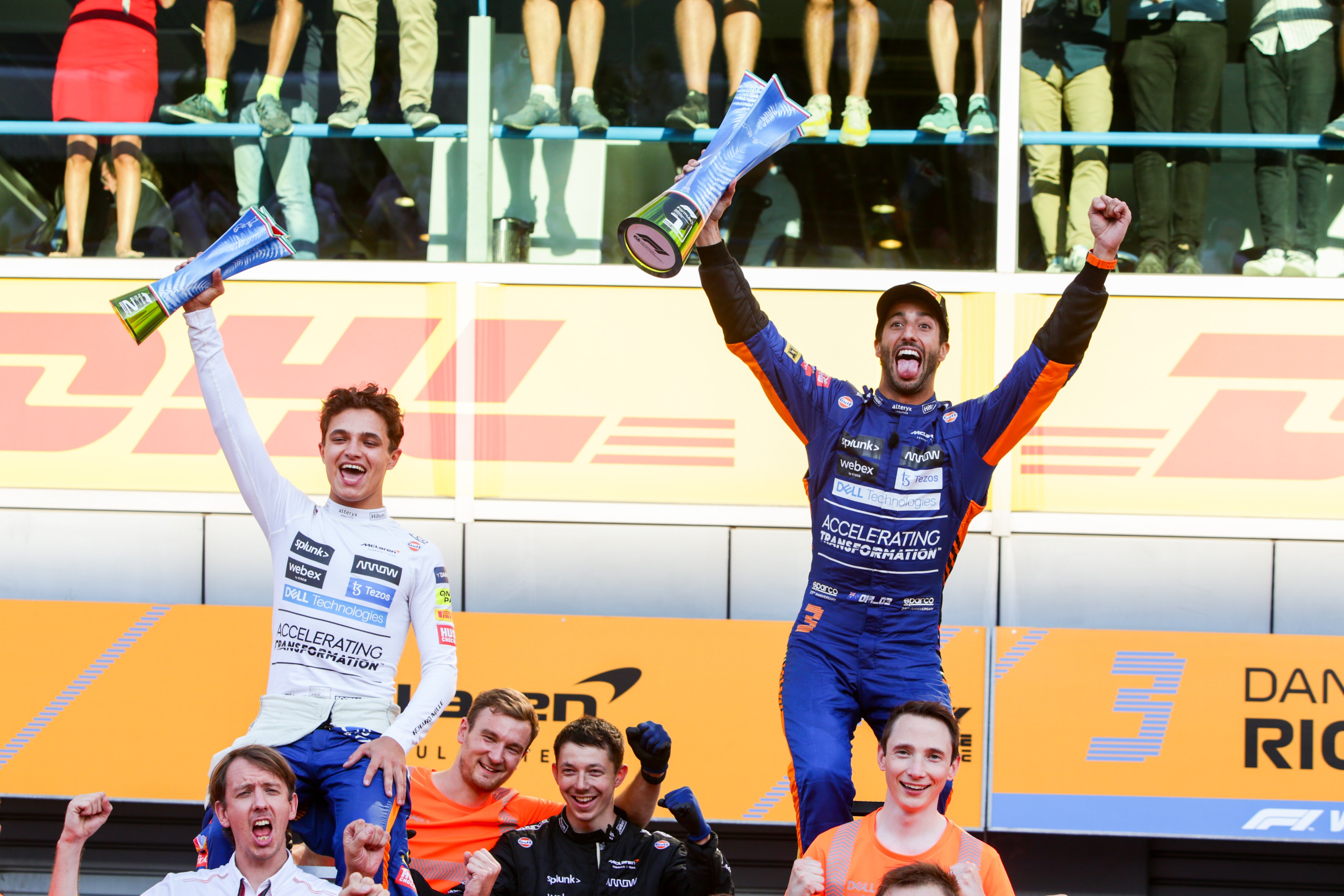 F1 drivers celebrate atop the shoulders of team members.