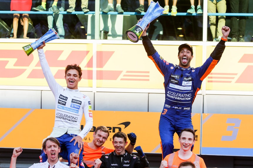 F1 drivers celebrate atop the shoulders of team members.