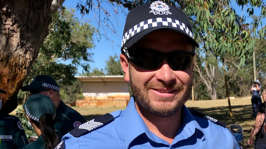 Sgt Michael Paterson from WA Police stands in his uniform with his hands on his hips and sunglasses on.