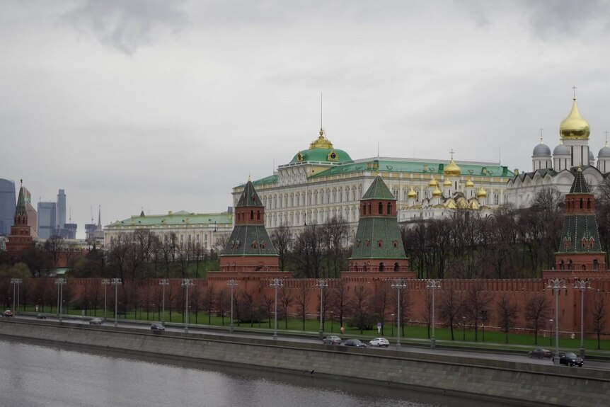 Gold domes can be seen among a cluster of buildings beside a river.