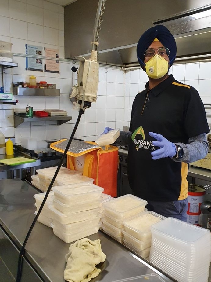 A man stands in a kitchen cooking indian food.