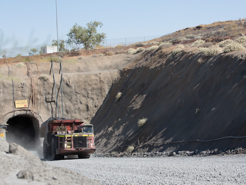 Truck emerging from hole at MMG Dugald River mine on dusty and rocky road out of mine entrance