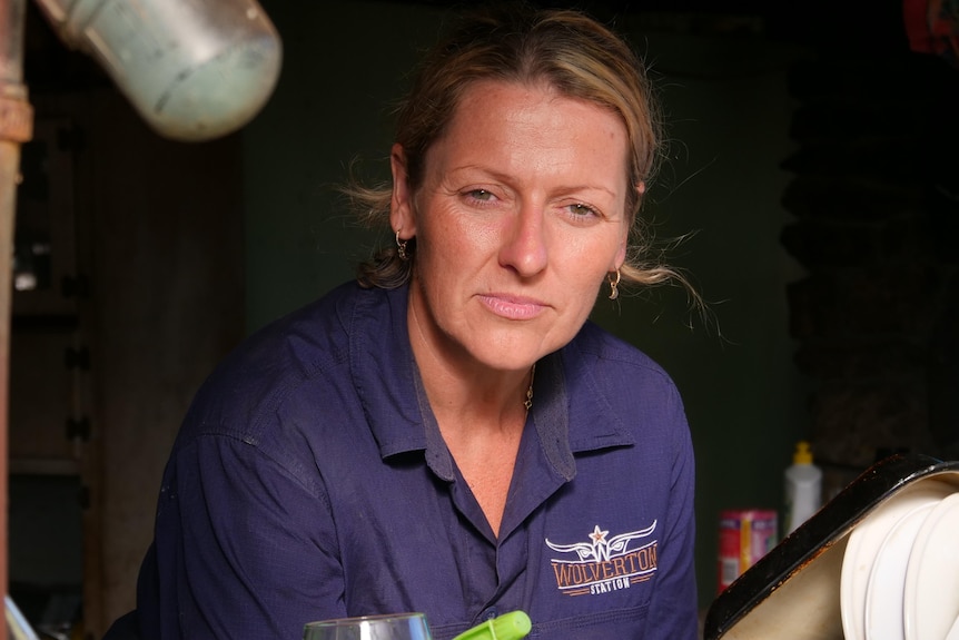 A woman stares out the kitchen window of a shack