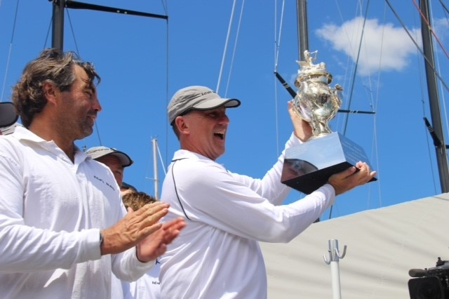 Skipper Matt Allen and a crew member hold up the winner's trophy onboard the winning yacht Ichi Ban