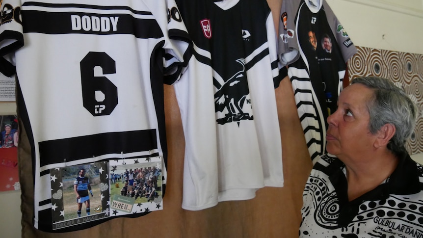 A lady looking up at three black and white football jerseys. 