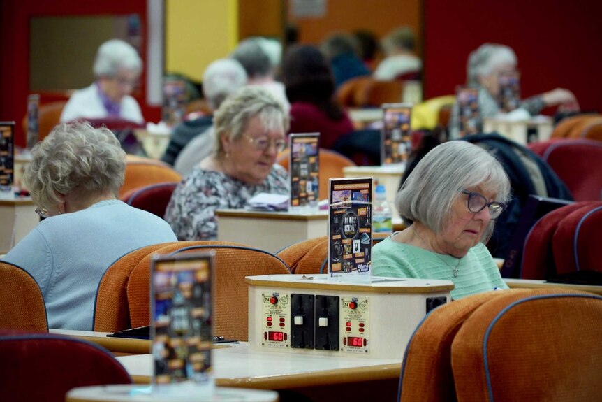 Women play bingo in a large bingo hall.