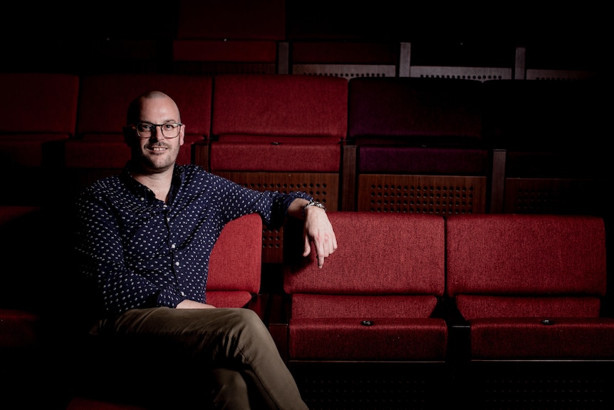 A man sits in otherwise empty theatre stalls