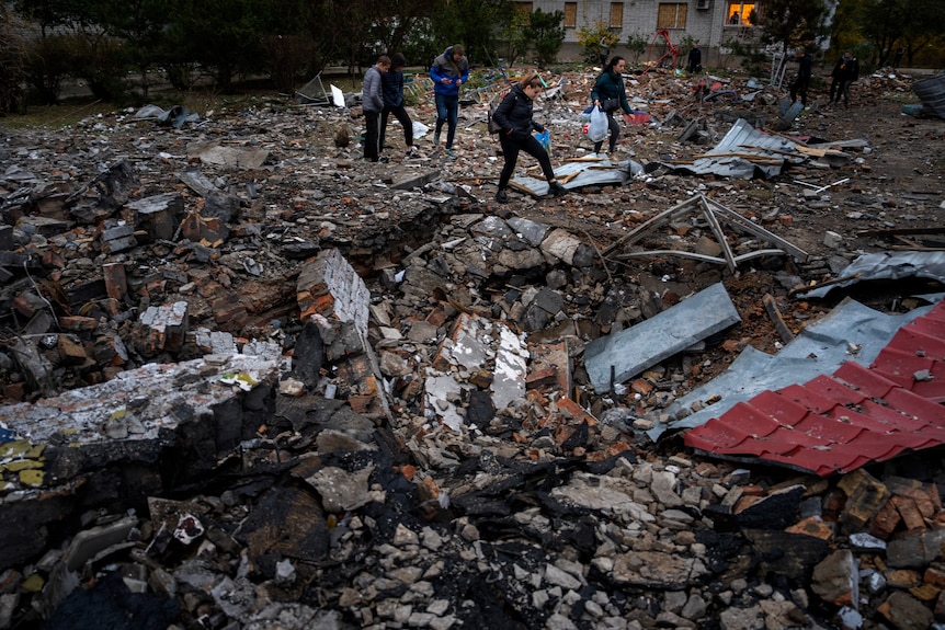 People walk on the rubble of an apartment building.
