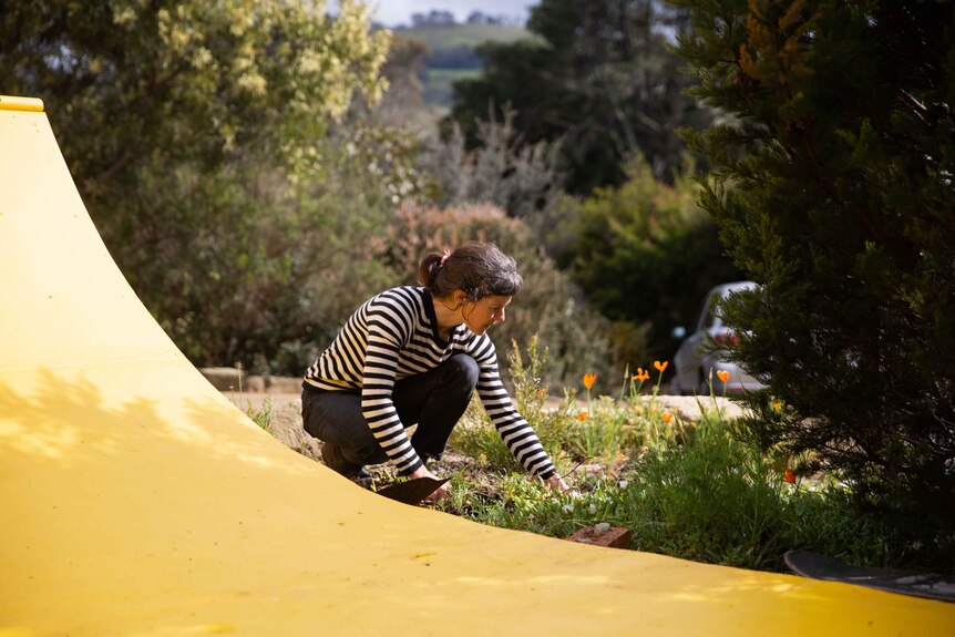 A woman crouching down in a garden.