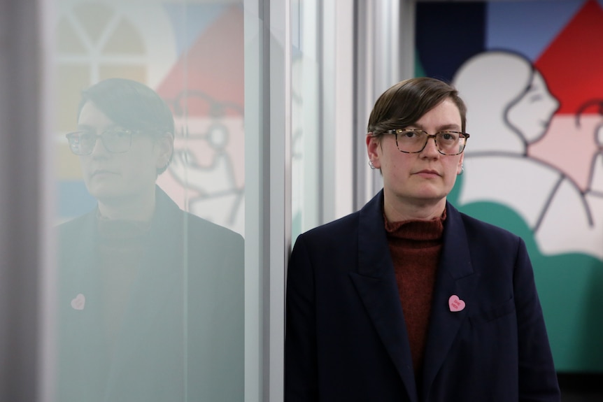 A woman wearing black glasses and a black blazer.