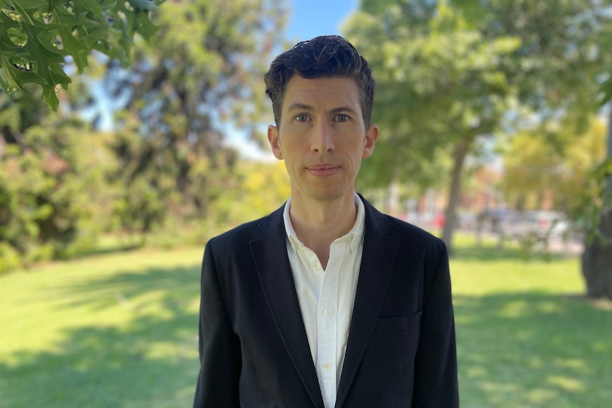 A man in a suit standing in a park