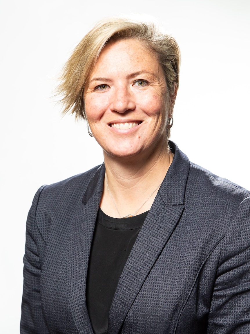 A smiling woman with short hair and a business jacket.