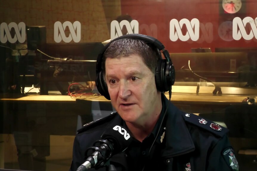 A man with short hair sits in the ABC studios with a police uniform on