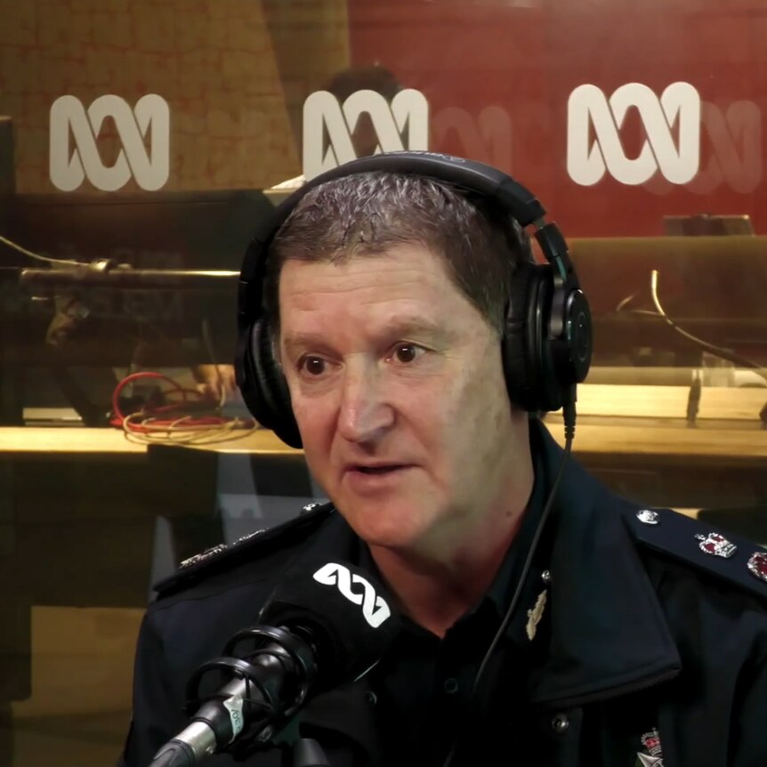 A man with short hair sits in the ABC studios with a police uniform on