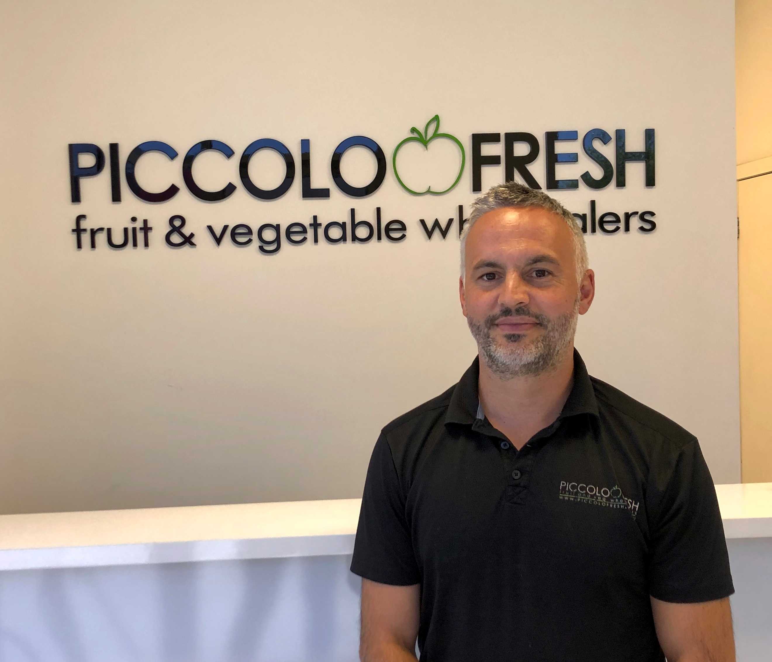 A man is standing in front of a sign that says Piccolo Fresh